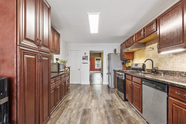 kitchen featuring decorative backsplash, a sink, dark wood-style floors, under cabinet range hood, and stainless steel appliances