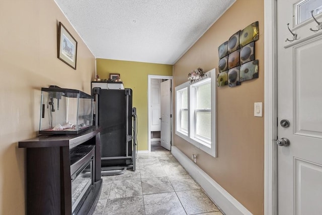 interior space with a textured ceiling and baseboards