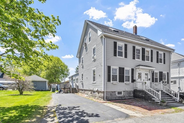 colonial-style house featuring a chimney and a front lawn