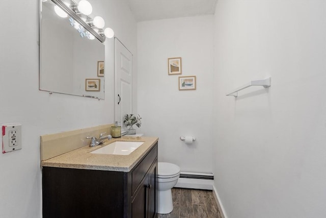 half bathroom featuring vanity, toilet, baseboards, wood finished floors, and a baseboard radiator