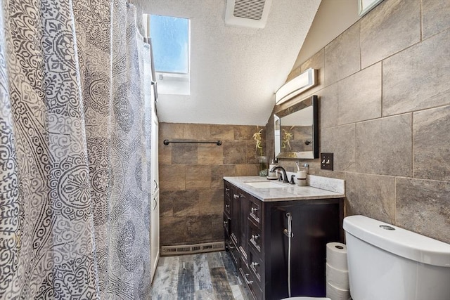 full bathroom with visible vents, lofted ceiling, toilet, and tile walls