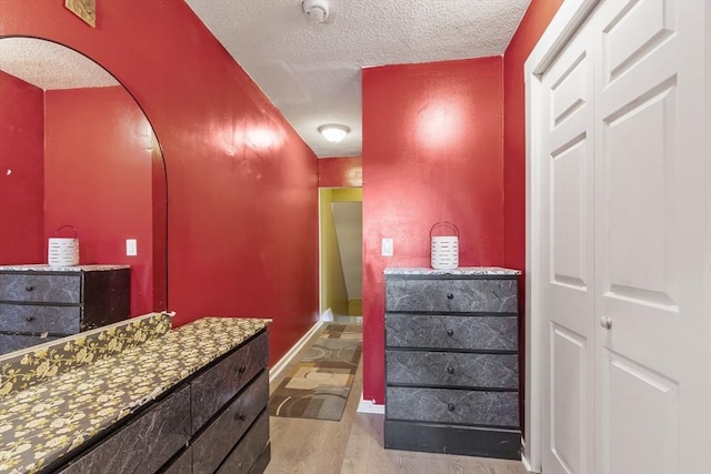 bathroom with baseboards, a textured ceiling, and wood finished floors