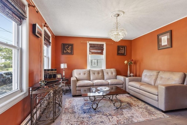 living room with plenty of natural light, a baseboard heating unit, a textured ceiling, and a chandelier
