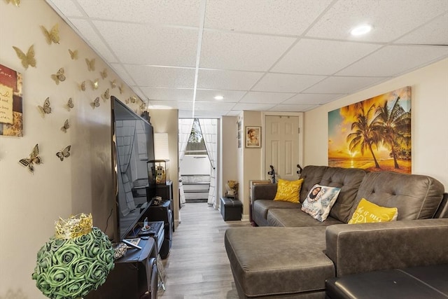 living area with a drop ceiling, wood finished floors, and stairway