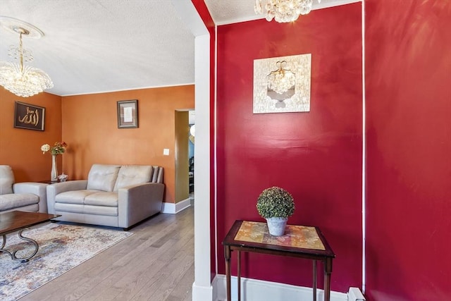 foyer with baseboards, a textured ceiling, a chandelier, and hardwood / wood-style flooring