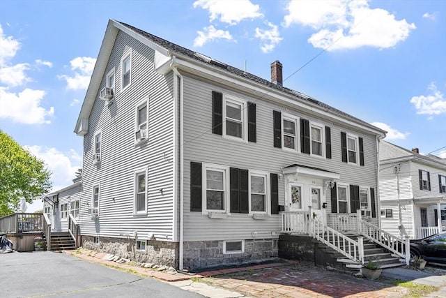 colonial house with a wooden deck and a chimney