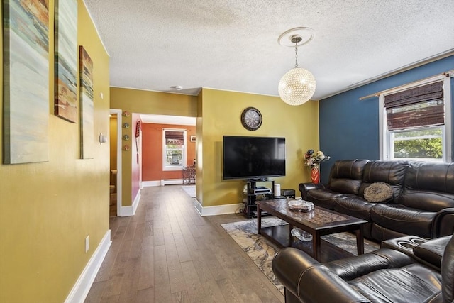 living area with an inviting chandelier, baseboards, dark wood-type flooring, a textured ceiling, and a baseboard heating unit