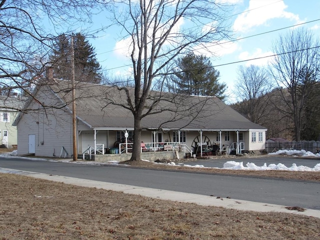 view of front facade featuring covered porch and a chimney