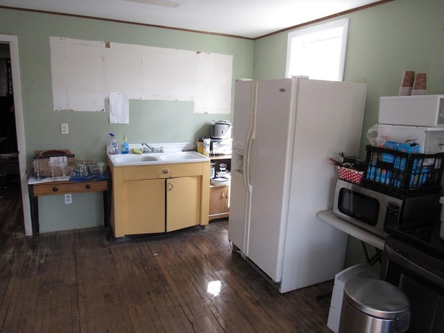 kitchen featuring a sink, stainless steel microwave, white refrigerator with ice dispenser, light countertops, and dark wood-style flooring