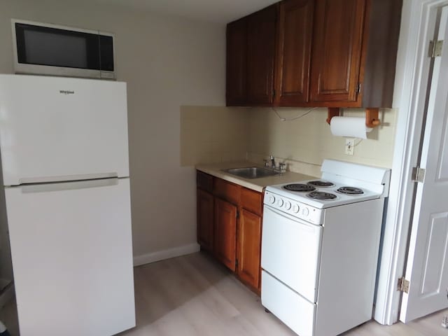 kitchen with light hardwood / wood-style floors, decorative backsplash, white appliances, and sink