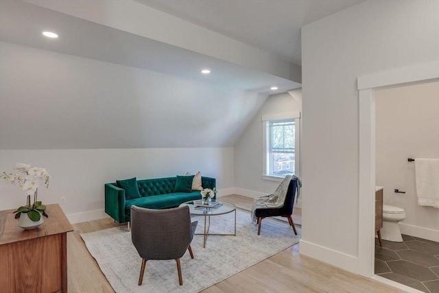 sitting room with light wood-type flooring and vaulted ceiling