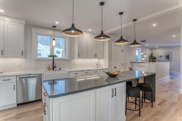 kitchen featuring hanging light fixtures, light hardwood / wood-style flooring, stainless steel dishwasher, and a kitchen island