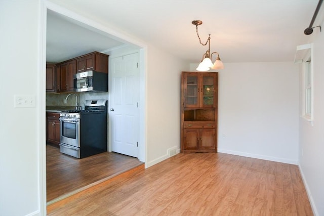 248 Levin Rd, Rockland, MA 02370 - kitchen featuring appliances with stainless steel finishes, light wood-style flooring, tasteful backsplash, and baseboards