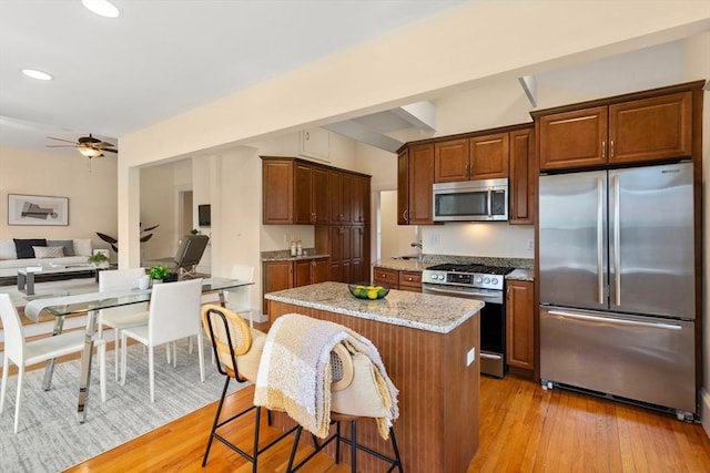 kitchen with a kitchen island, recessed lighting, light stone counters, a ceiling fan, and appliances with stainless steel finishes