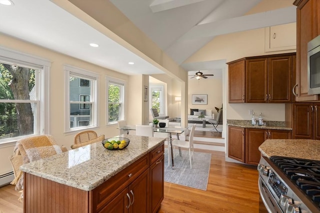 kitchen with lofted ceiling, light stone countertops, recessed lighting, stainless steel range with gas stovetop, and light wood finished floors