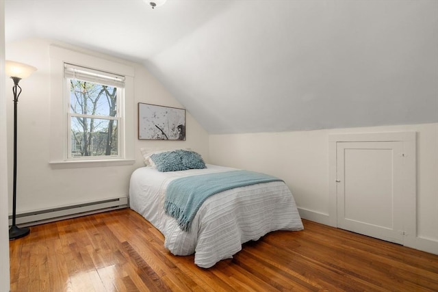 bedroom featuring wood finished floors, a baseboard heating unit, and vaulted ceiling