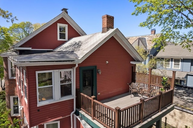 rear view of property with a chimney and a deck