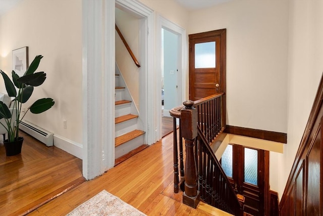 stairway featuring baseboards, wood finished floors, and a baseboard radiator