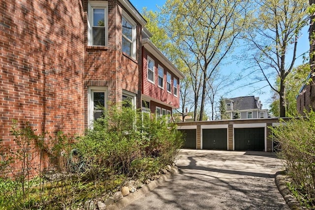 view of side of property featuring brick siding and a garage