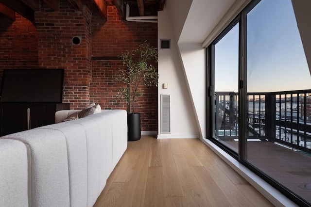 living room with brick wall and light hardwood / wood-style floors