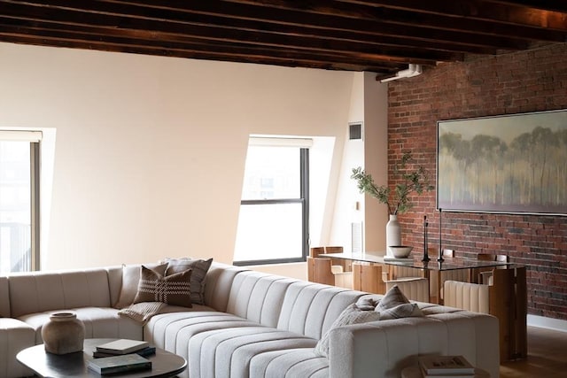 living room with beam ceiling, wood-type flooring, and brick wall