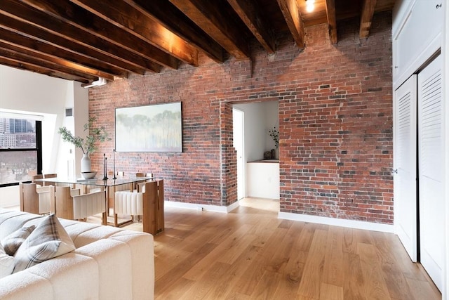 living room featuring brick wall, beam ceiling, and light hardwood / wood-style flooring