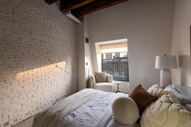 bedroom featuring beamed ceiling, brick wall, and a high ceiling