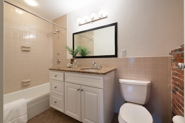 full bathroom with vanity, tiled shower / bath, tile walls, and toilet