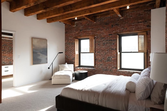 carpeted bedroom with multiple windows, beam ceiling, and brick wall