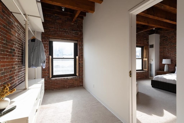 corridor with brick wall, beam ceiling, and light carpet