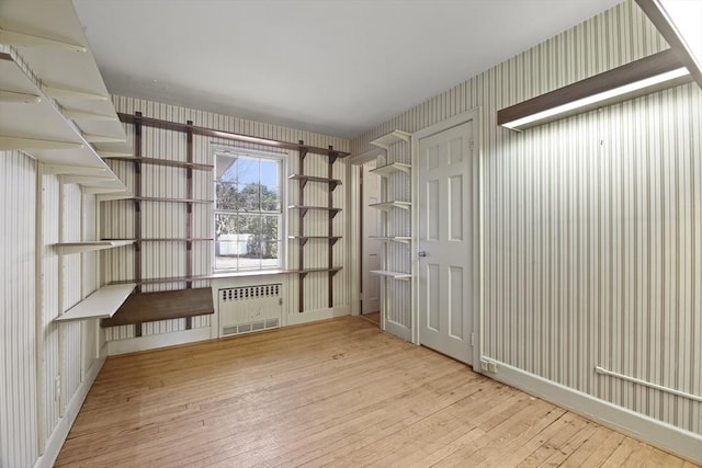 interior space featuring wallpapered walls, radiator heating unit, and hardwood / wood-style flooring