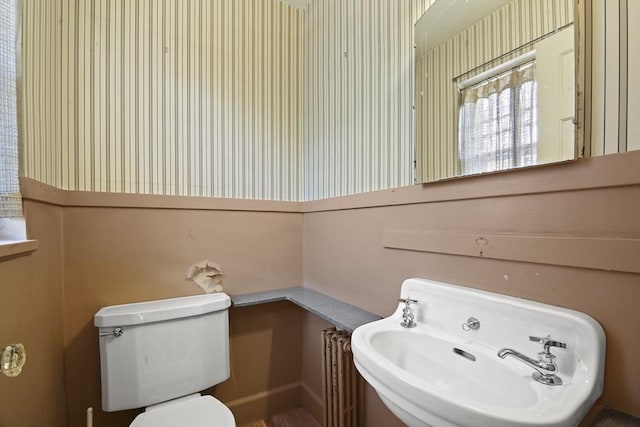 bathroom featuring wallpapered walls, toilet, and a sink