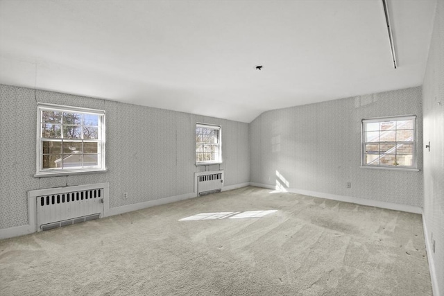 spare room featuring wallpapered walls, vaulted ceiling, radiator heating unit, and carpet floors