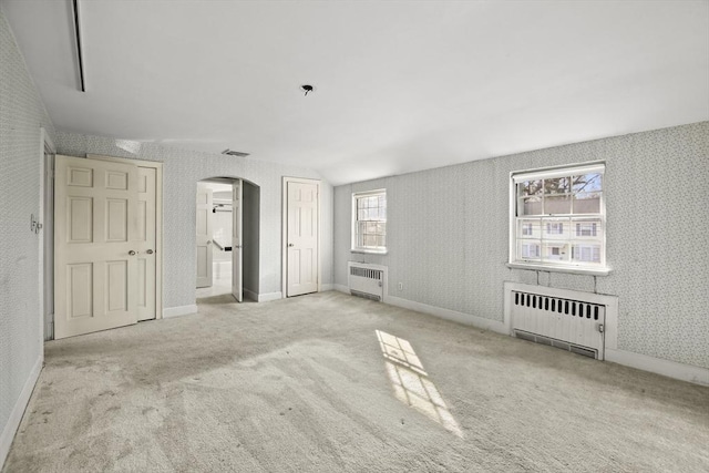 interior space with wallpapered walls, radiator, visible vents, and arched walkways