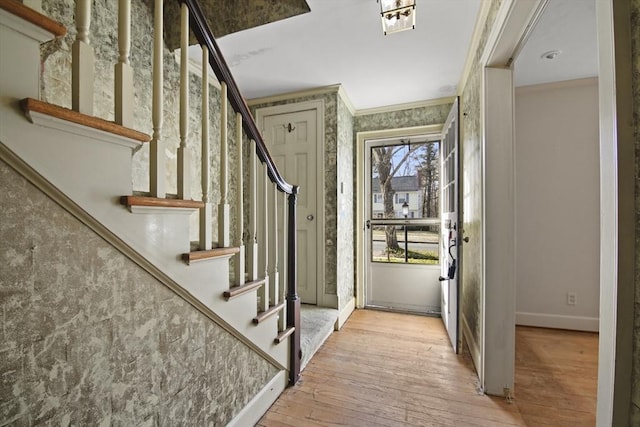 foyer entrance featuring stairway, wood-type flooring, baseboards, and ornamental molding