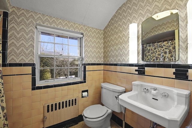 full bathroom featuring toilet, a sink, radiator heating unit, tile walls, and wallpapered walls