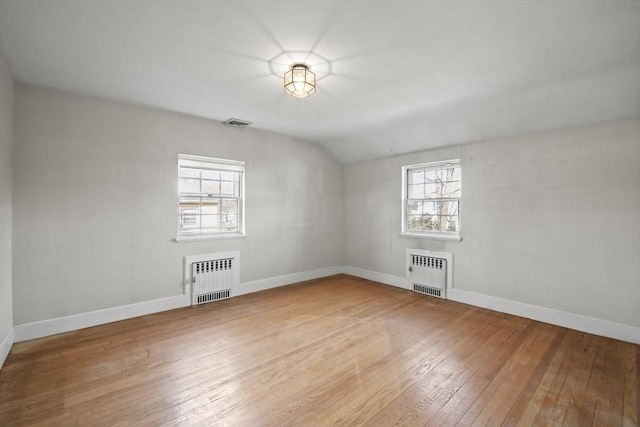 empty room with radiator heating unit, light wood-style floors, and baseboards