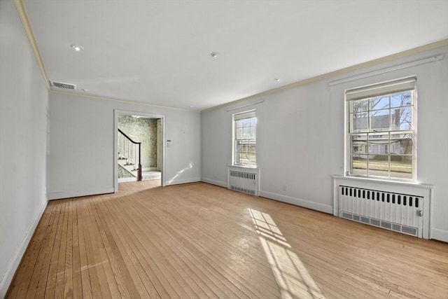 spare room with light wood-style flooring, crown molding, stairs, and radiator heating unit