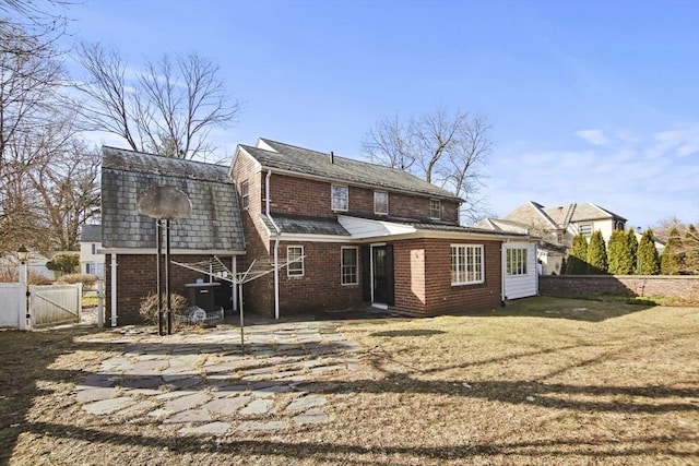 rear view of house with central air condition unit, fence, brick siding, and a gate