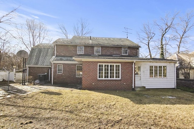 back of property with brick siding, fence, central air condition unit, entry steps, and a lawn