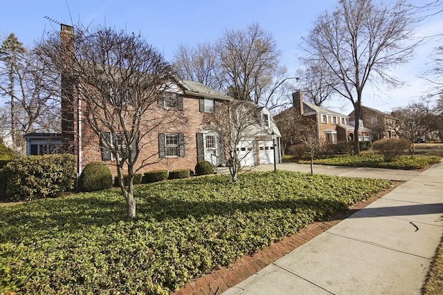 view of front of house featuring concrete driveway, a garage, a front yard, and a chimney