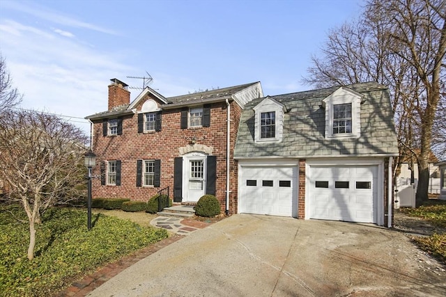 view of front of home featuring brick siding, driveway, and a chimney