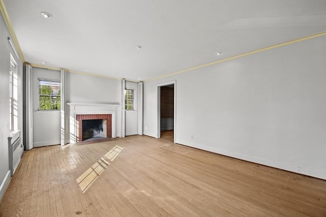 unfurnished living room with light wood-type flooring, baseboards, a brick fireplace, and ornamental molding