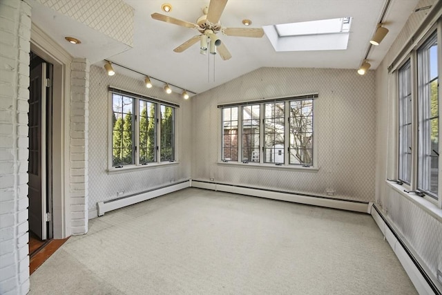 unfurnished sunroom with track lighting, vaulted ceiling with skylight, a baseboard heating unit, and ceiling fan