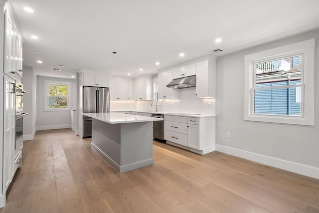 137-139 Crafts St, Newton, MA 02460 - kitchen with under cabinet range hood, appliances with stainless steel finishes, baseboards, light wood finished floors, and recessed lighting