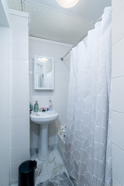 bathroom featuring shower / tub combo and tile walls