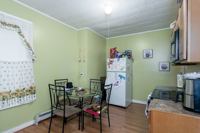 dining room with ornamental molding, baseboard heating, and light hardwood / wood-style flooring