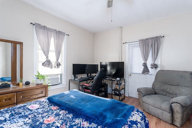 bedroom with cooling unit, hardwood / wood-style flooring, and multiple windows