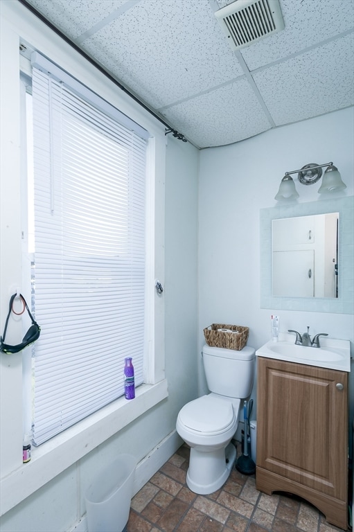 bathroom with a drop ceiling, vanity, and toilet