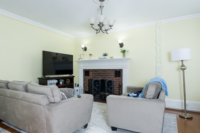 living room with ornamental molding, a brick fireplace, a chandelier, and light hardwood / wood-style floors